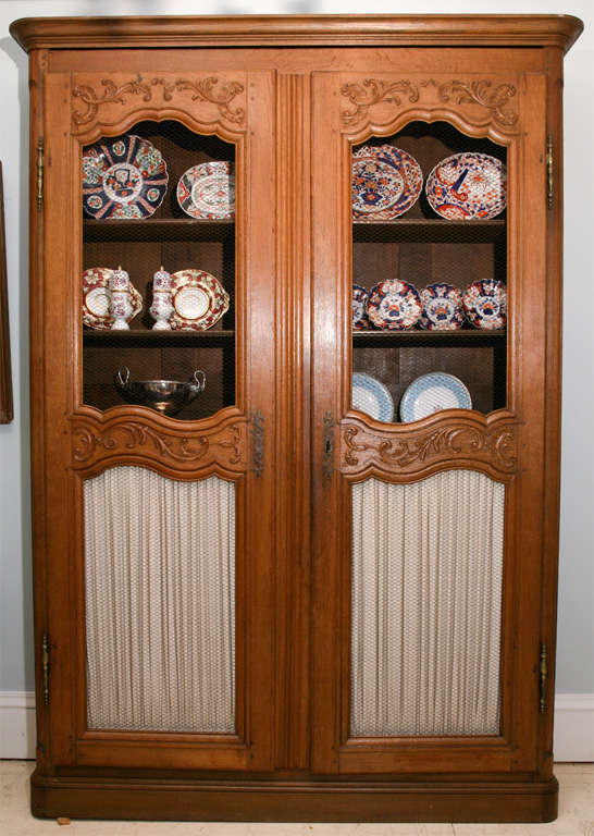 French Provinciaal 19th century bookcase with wire mesh doors, floral carving and<br />
brass hardware.  Five shelves.